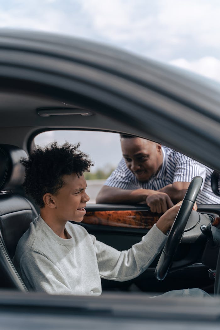 Crafting Captivating Headlines: Your awesome post title goes here Father instructs son in car driving lesson inside a vehicle on a sunny day.